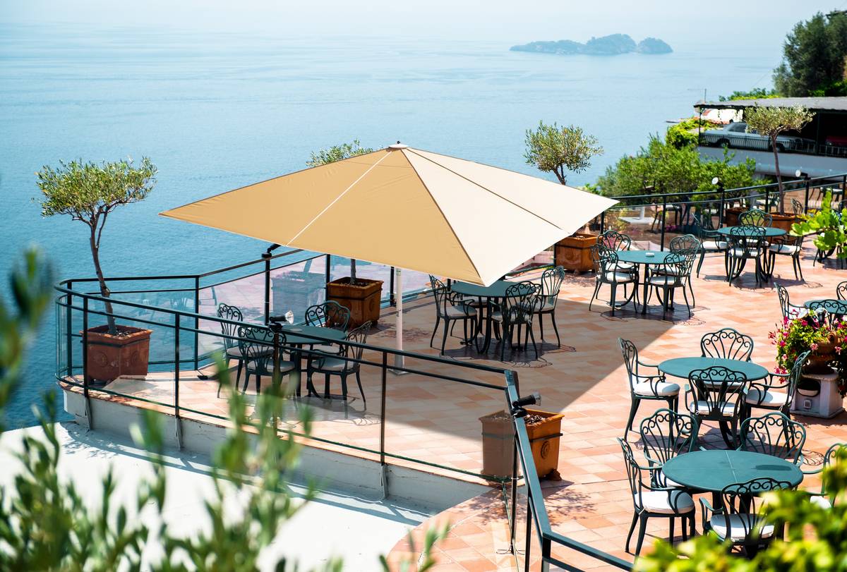 Sonnige Gastro-Terrasse mit großem Schirm und weitem Meerblick