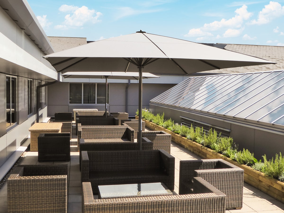 4x4 Sonnenschirm schützt moderne Rattanmöbel auf Dachterrasse