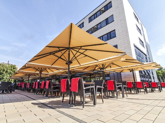 Gastronomie-Terrasse mit vielen Sonnenschirmen vor Gebäude